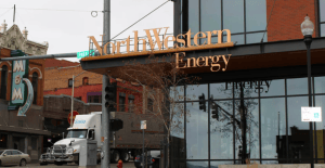 A city street scene featuring the NorthWestern Energy building with its large glass windows and golden signage.